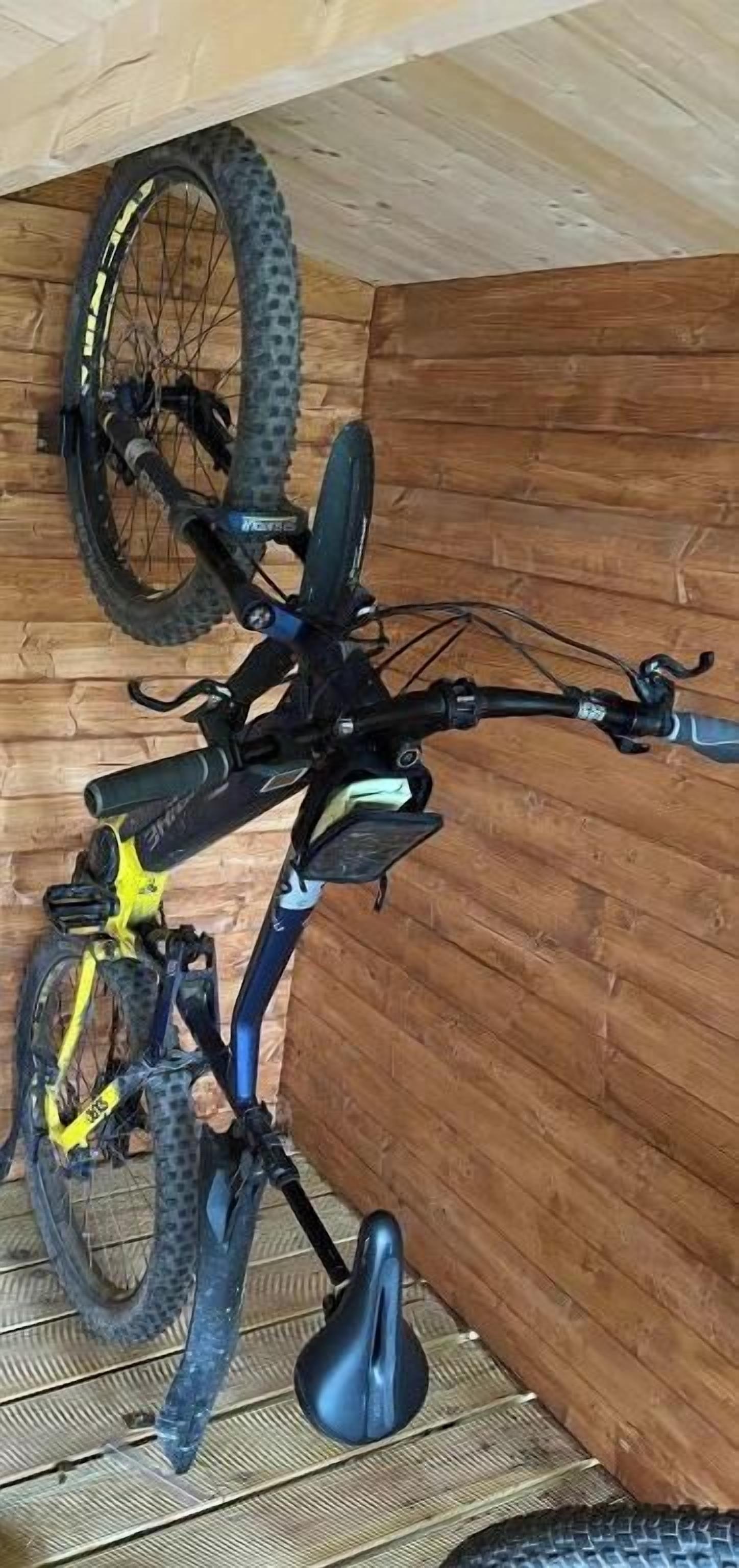 Een fiets leunt tegen een houten muur in een kamer met een schuine plafond.