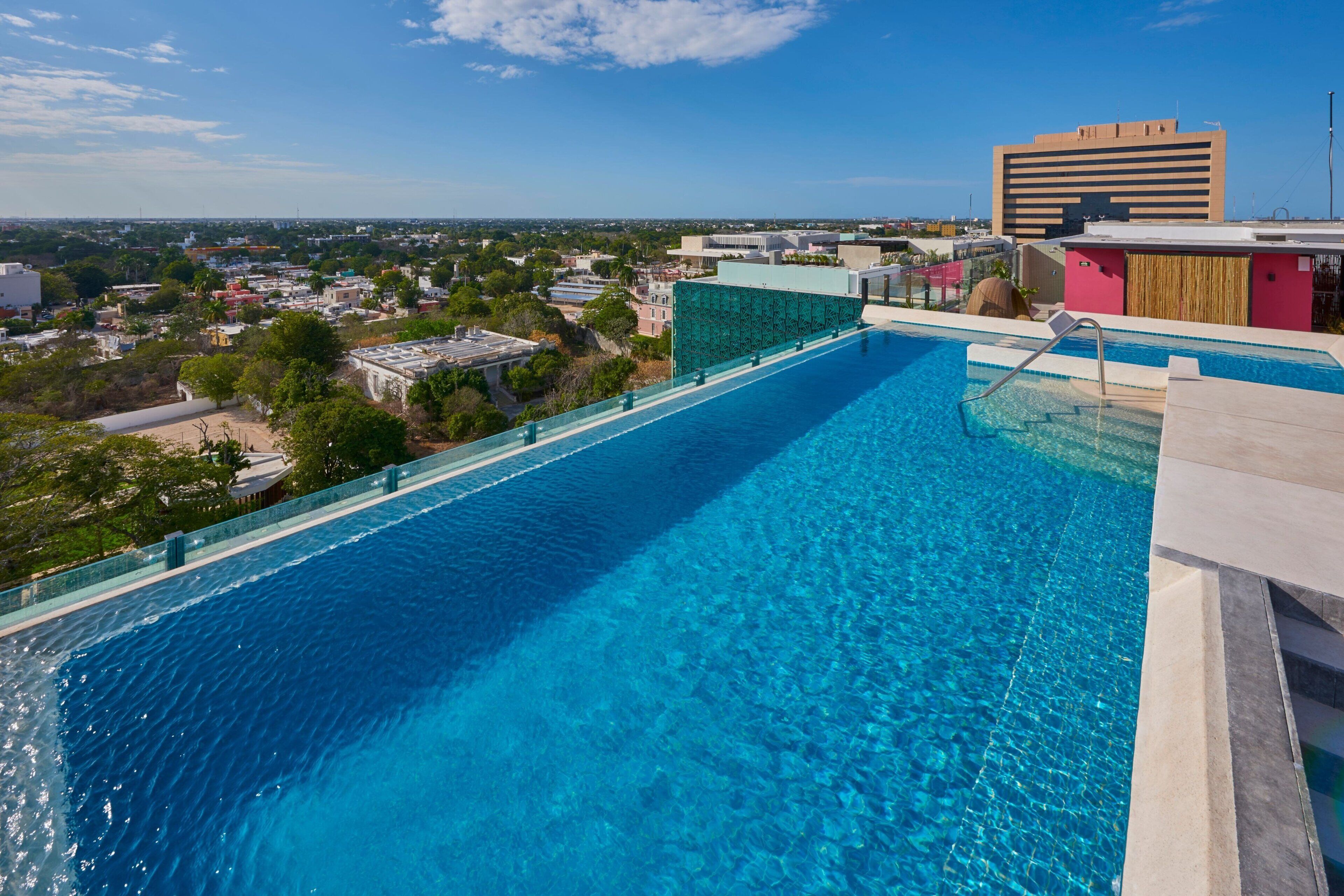 Una piscina al aire libre, sombrillas, sillones reclinables de piscina