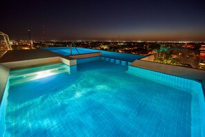 A rooftop infinity pool with a city view at night. - City Express Plus by Marriott Mérida (Mérida)