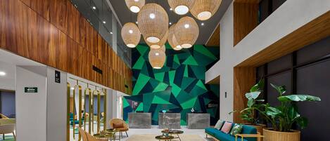A modern lobby with a geometric wall design, wooden paneling, and a seating area with a sofa and chairs.