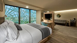 A modern hotel room with a large bed, a desk, a sofa, and a TV. - City Express Plus by Marriott Mérida (Mérida)