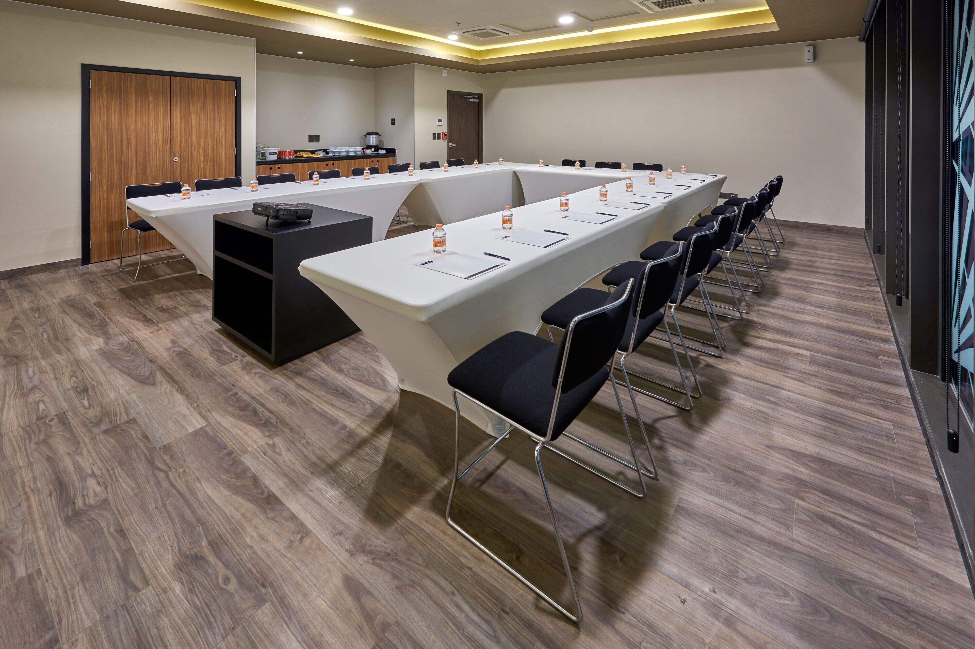 A conference room with a long table, chairs, and a coffee station.