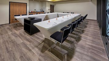 Un salón de conferencias con una larga mesa, sillas y una estación de café.