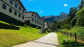 A cobblestone street flanked by buildings with traditional architecture, leading towards a mountainous backdrop. - Studio Petrópolis Alameda das Pedras (Petrópolis)