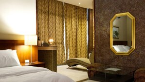 A hotel room with a bed, a desk with a lamp, a chair, a small table, and a large mirror on the wall. - Hotel Casa Miller (Panama City)
