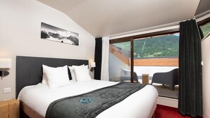Ein Hotelzimmer mit Bett, Ausblick ins Freie, einem Sessel und einem kleinen Tisch.