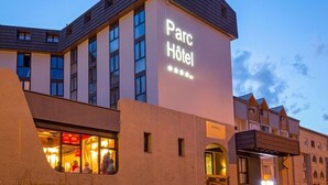 Ein Hotel im modernen Stil, mit einem auffälligen Schild mit der Aufschrift "Parc Hotel" und einem gut sichtbaren Eingang mit Glasfassade.