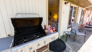 A portable gas grill with controls, a chair, and a bag of chips on a porch. - Arbor Inn Motel Oakridge (Oakridge)