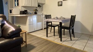A compact kitchen with white cabinets and a dining table set for two. - Arbor Inn Motel Oakridge (Oakridge)