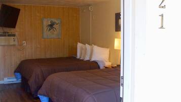 A room with two beds, a wooden wall, a ceiling light, and a door with the number 21.