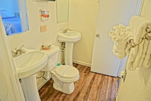 Casa de banho com sanita, lavatório e bidé. Há um porta-toalhas com uma toalha pendurada.
