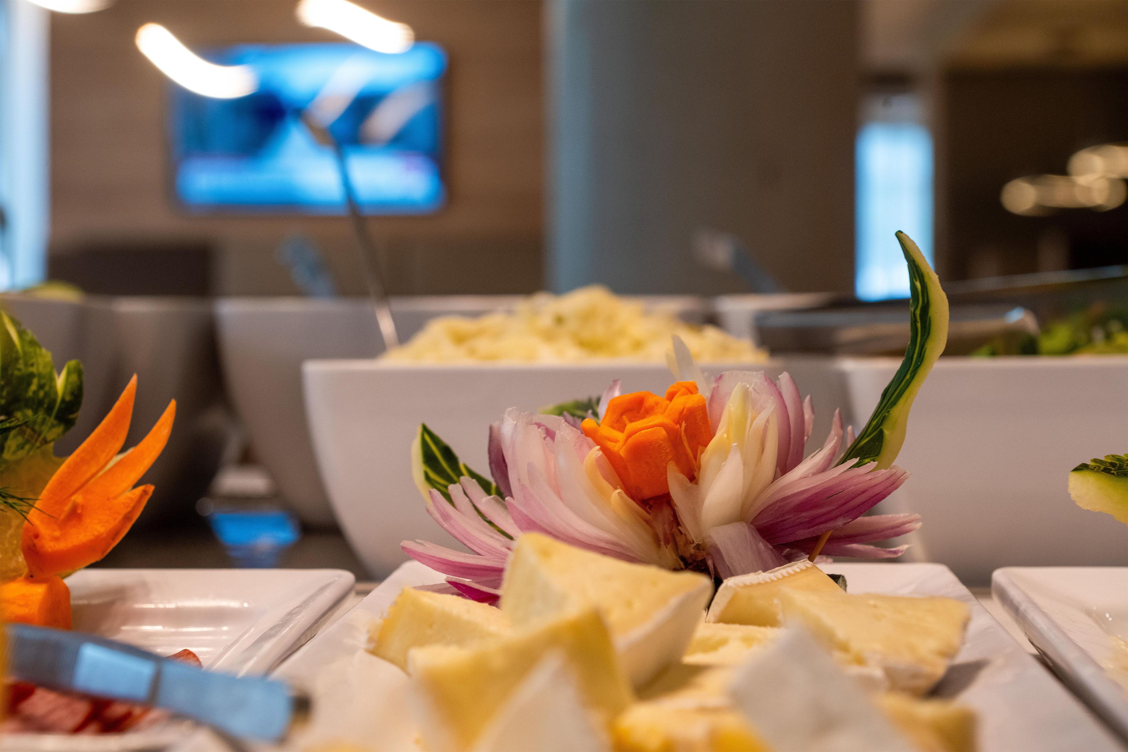A buffet with various food items and a decorative flower arrangement.