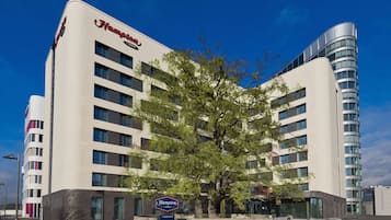 Stylish hotel building with a prominent entrance, surrounded by lush greenery.