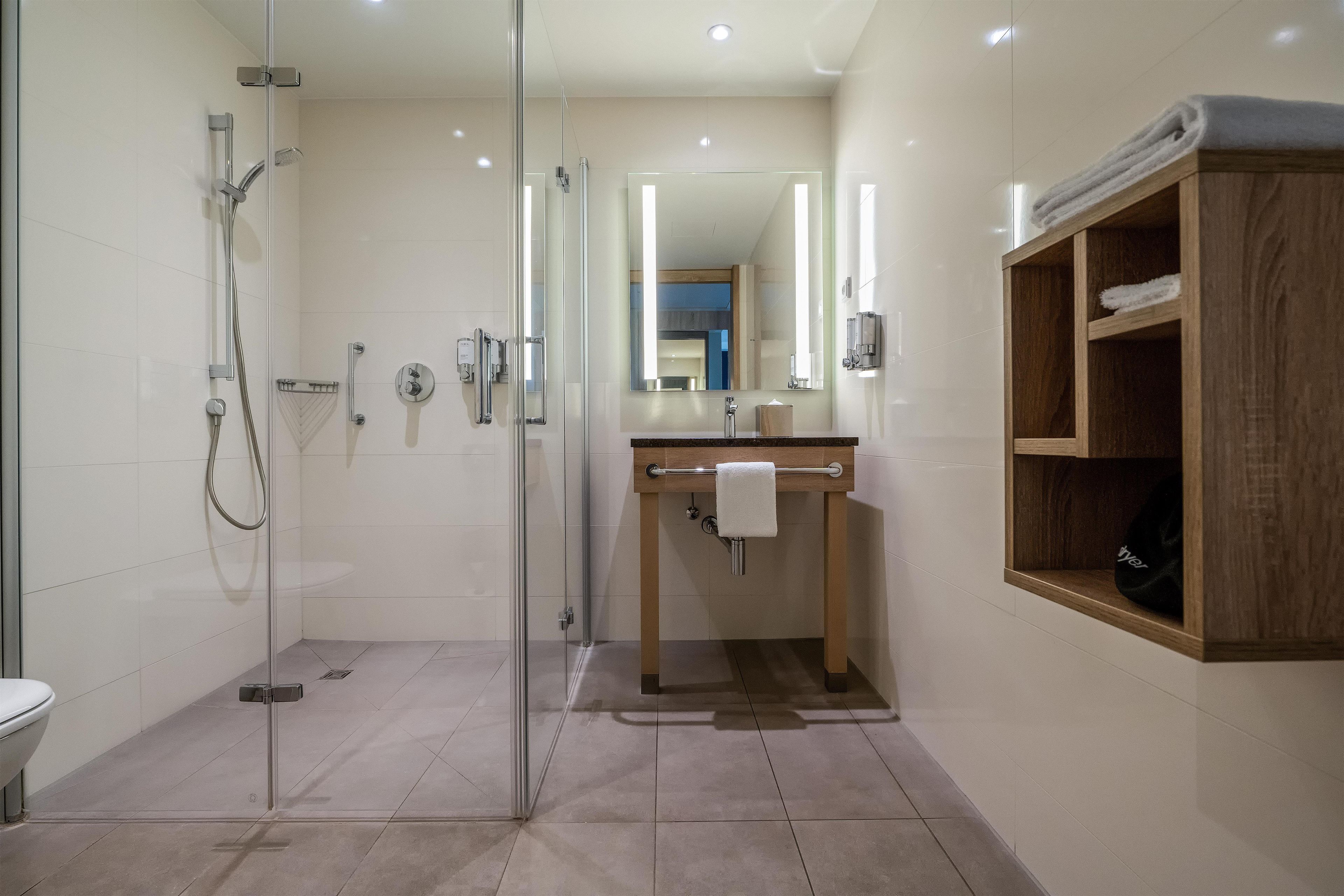 Ein modernes Badezimmer mit einer Duschkabine aus Glas, einem Holzbadezimmer-Möbel und einem Spiegel.