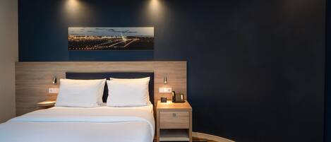 Habitación de hotel con cama, mesitas de noche, un teléfono y un cuadro colgado en la pared.