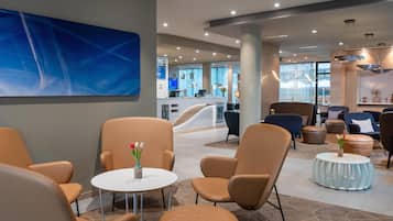 A modern lounge area with leather chairs, a round table, and a blue abstract painting on the wall.