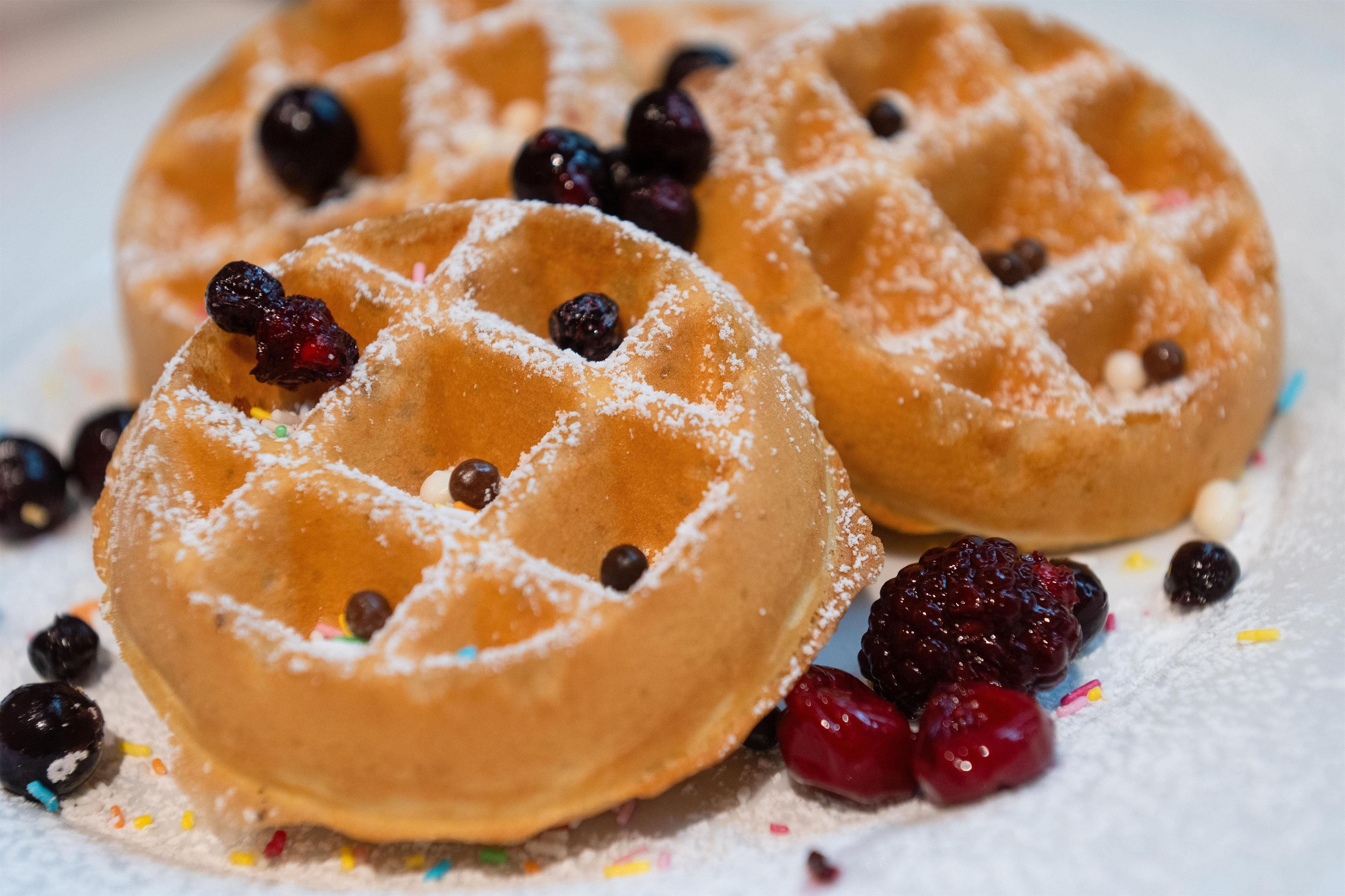 Two waffles with powdered sugar and berries.