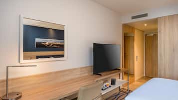 Habitación de hotel con cama, escritorio con televisor de pantalla plana, silla, cuadro en la pared y puerta que da a otra habitación.