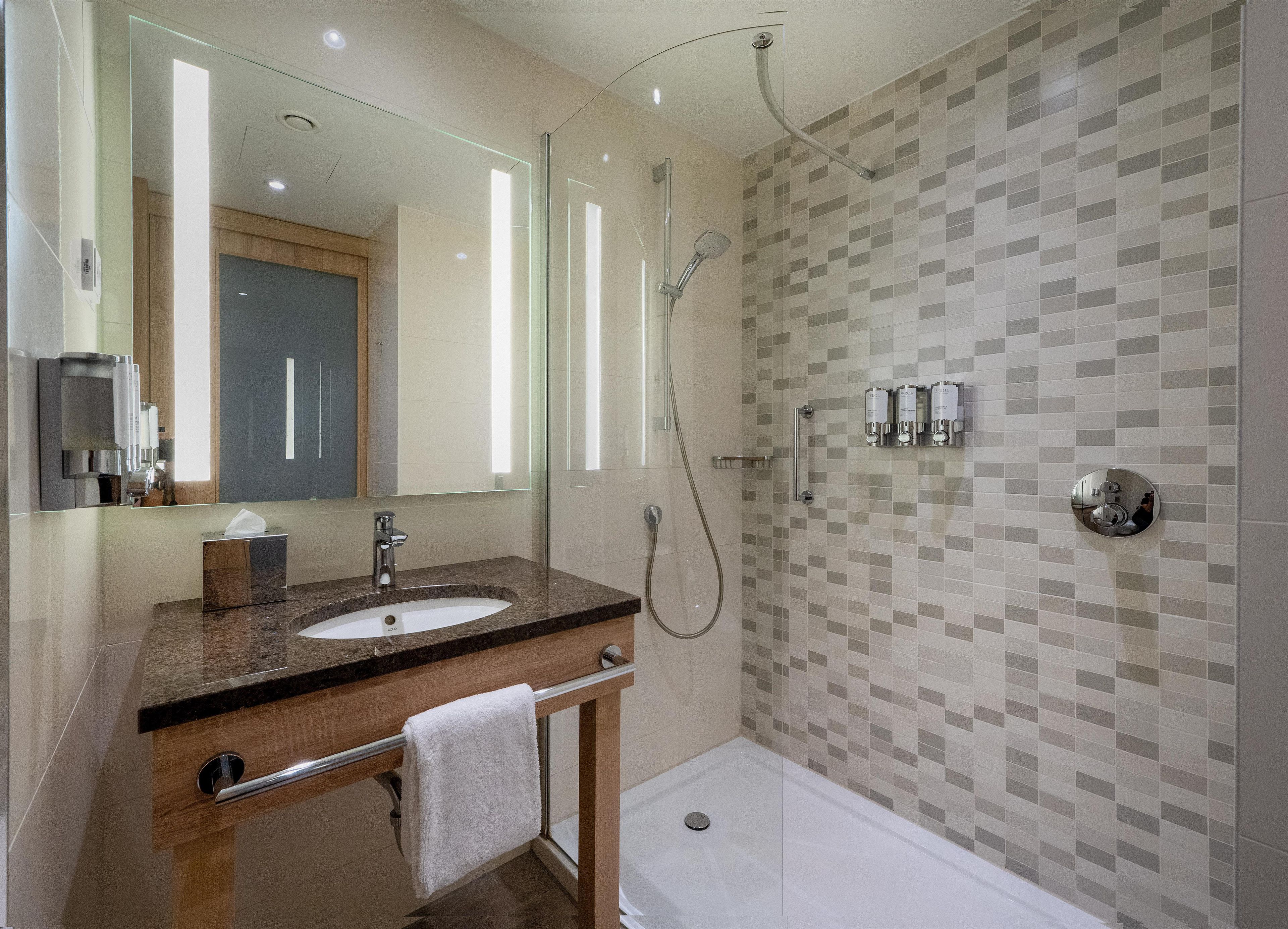 Une salle de bain moderne avec un lavabo, un miroir et une douche.