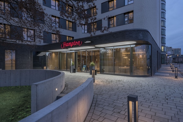 Un hotel moderno con fachada curva, amplios ventanales y un área de entrada bien iluminada.