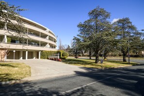 Un edificio de varios pisos con una fachada curva, un estacionamiento y un césped bien cuidado.