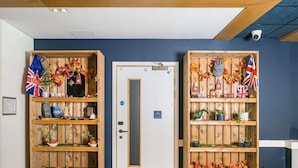 A hotel reception area with wooden shelving units decorated with autumn leaves and flags. - Ibis Budget London Whitechapel - Brick Lane (London)