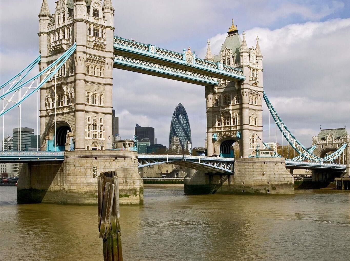 A historic stone bridge with intricate architecture and a modern glass building in the background.