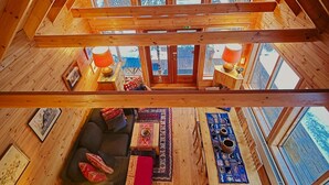 Un interno in legno con soffitti alti e disposizione in stile loft, con un divano, tappeti e zona pranzo.