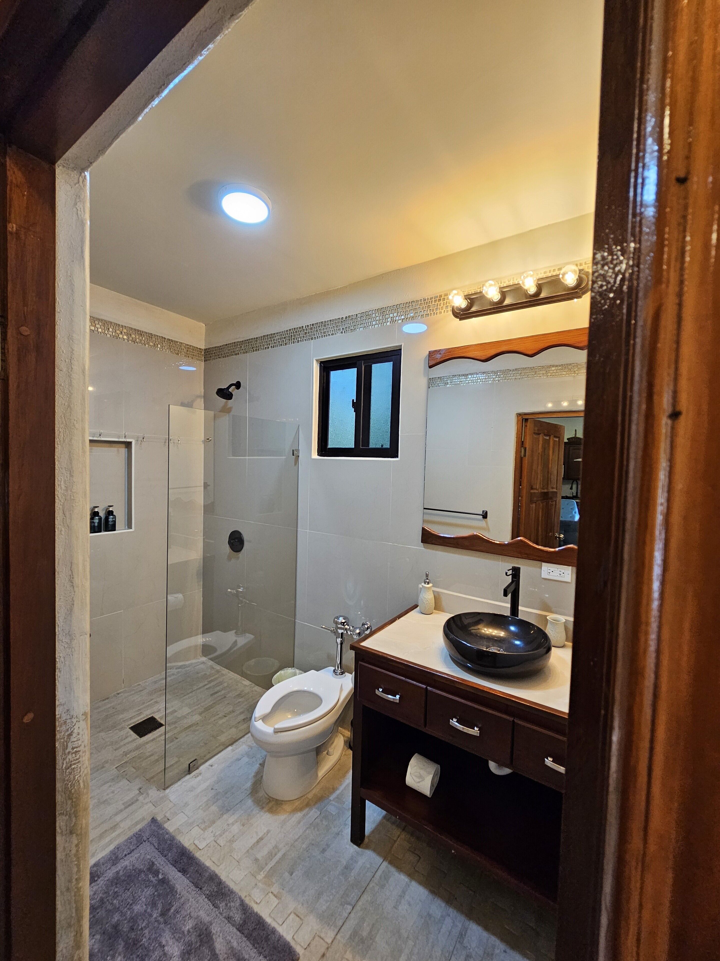 A modern bathroom with a glass-enclosed shower, a toilet, and a vanity with a sink.