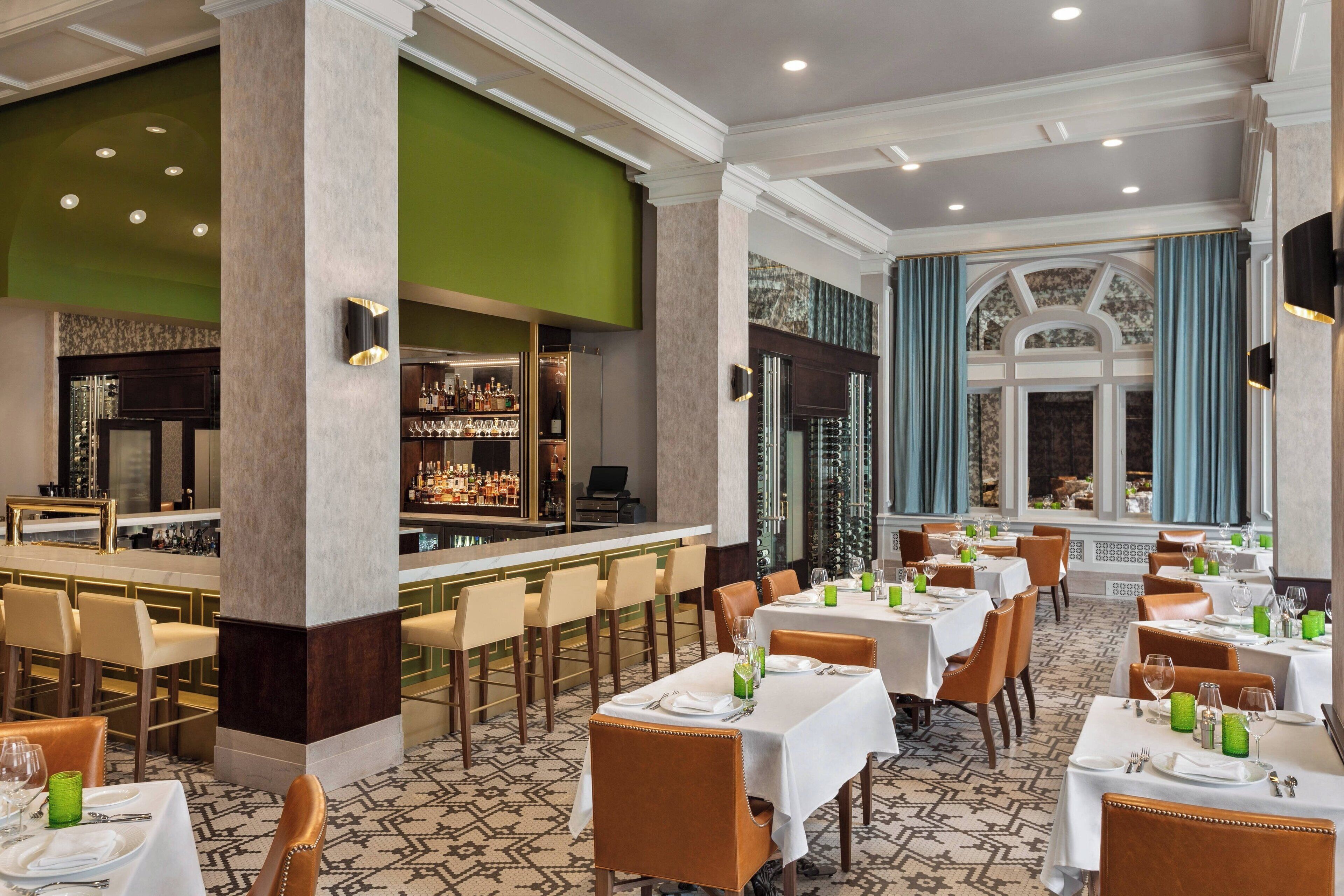 Een restaurant met meerdere tafels en stoelen, een bar en een vloer met een patroon.