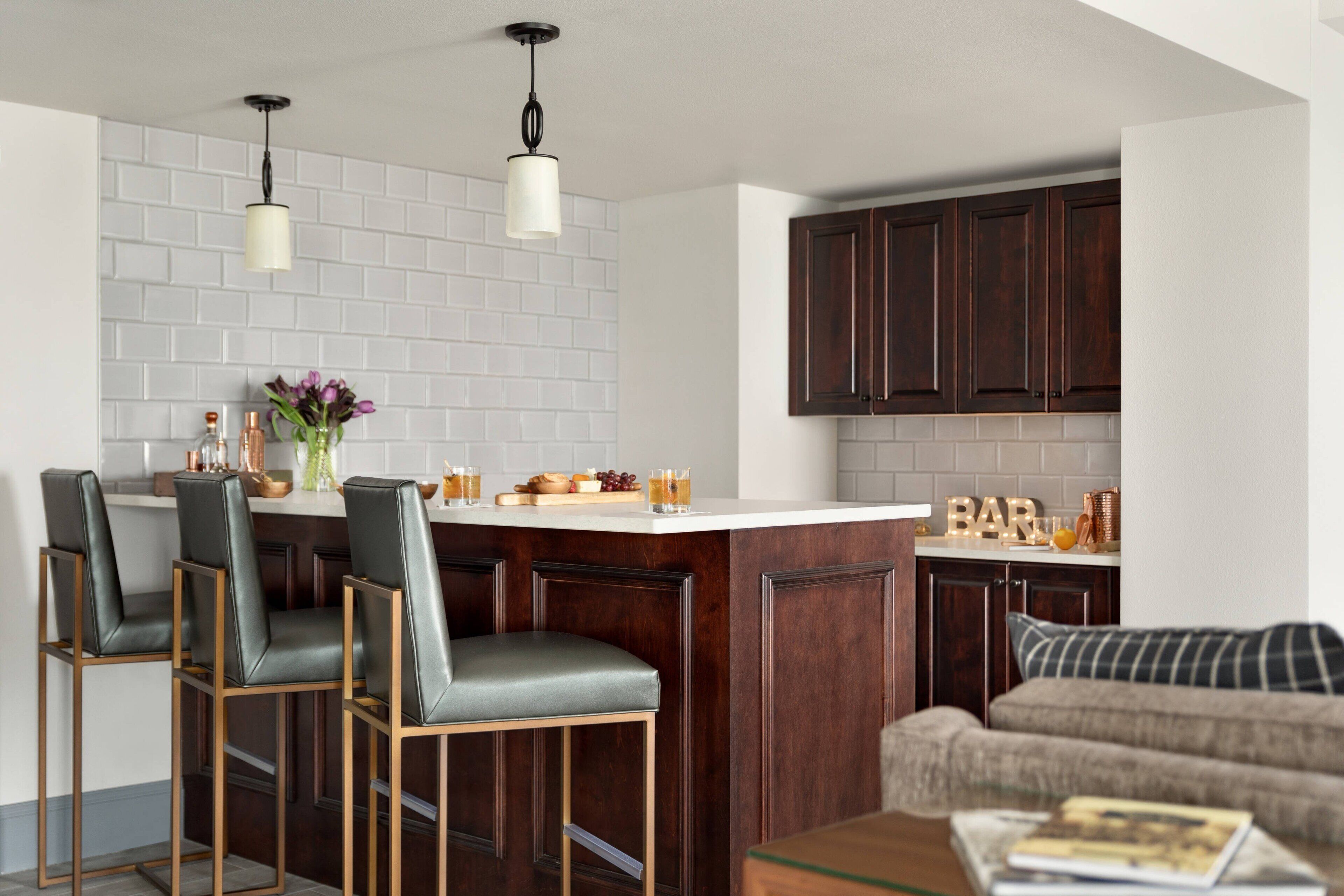 Een moderne keuken met een centraal eiland, een paar barkrukken en donkere houten kastjes.