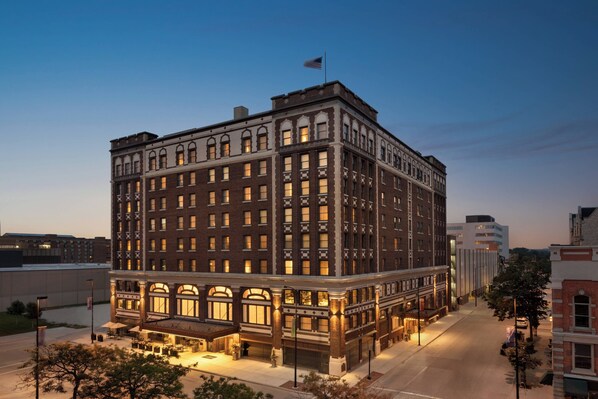 A historic hotel with a classic architectural design, featuring multiple floors and a prominent entrance with outdoor seating. - Hotel Northland, Autograph Collection (Green Bay)