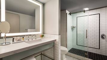A modern bathroom with a large mirror, a sink, and a glass-enclosed shower.