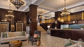 A spacious lobby with a grand staircase, a reception desk, and elegant chandeliers. - Hotel Northland, Autograph Collection (Green Bay)