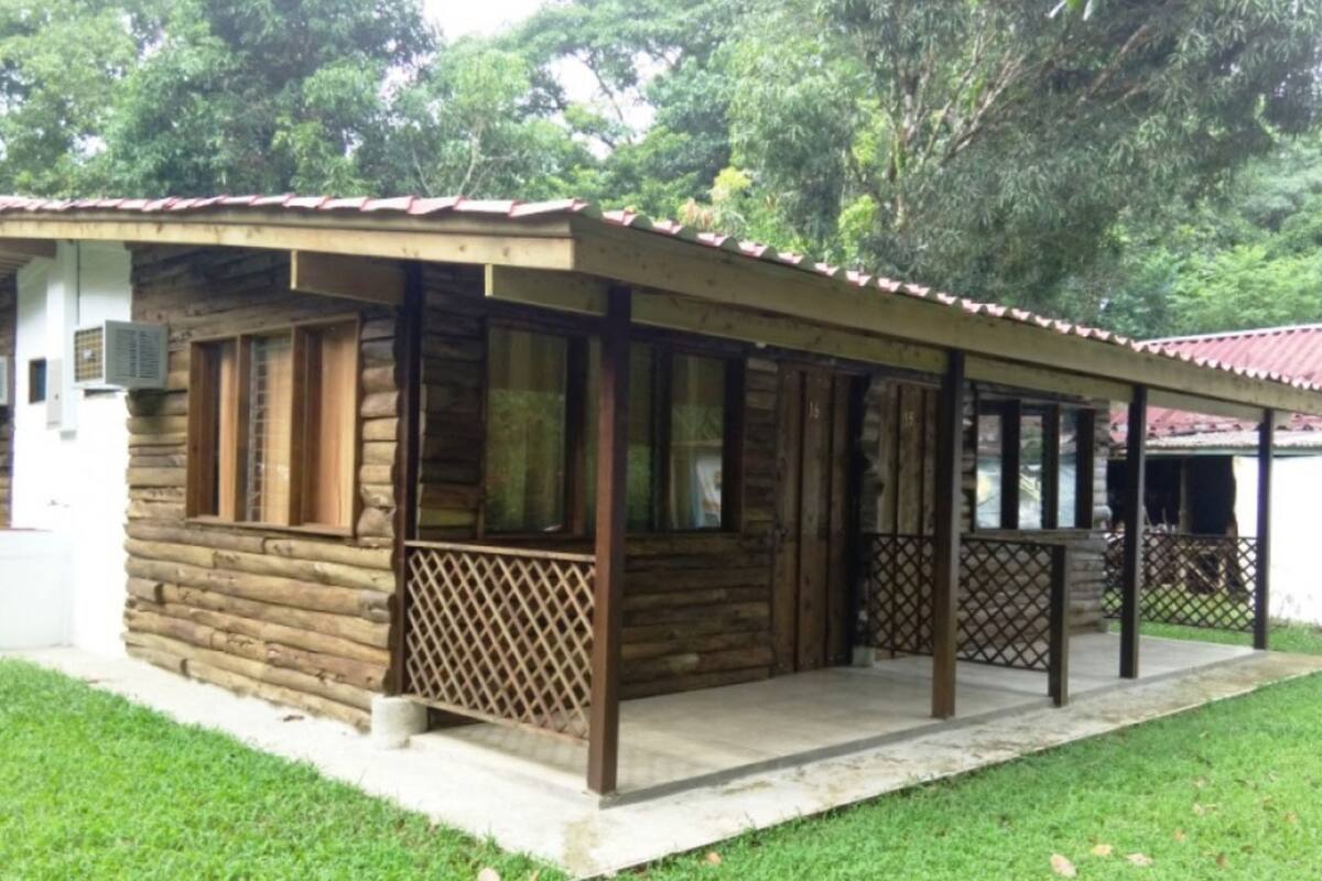 A log cabin with a covered porch and a fenced patio area.