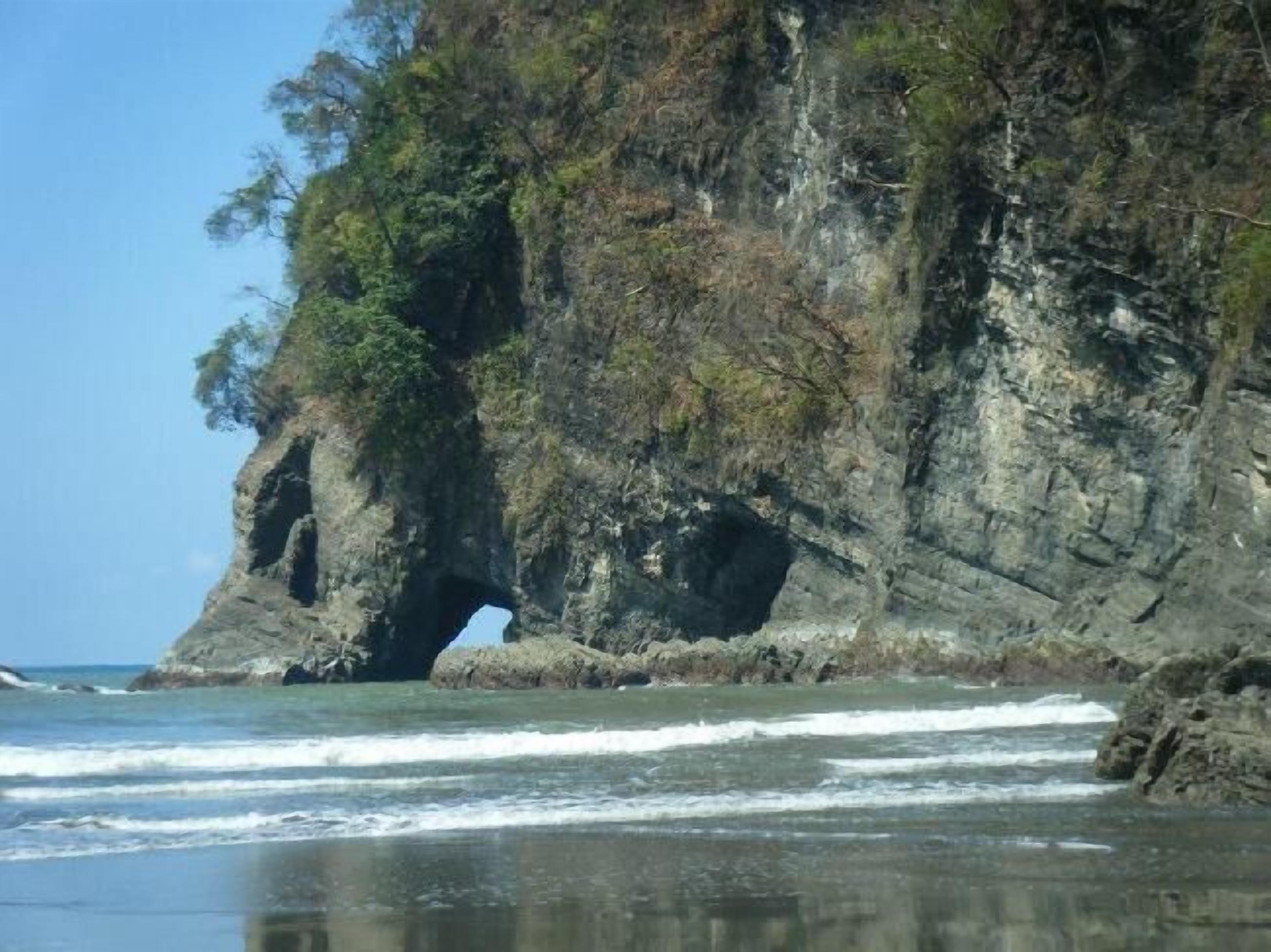 Un paisaje costero con una formación rocosa destacada que presenta un arco natural.
