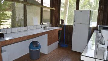 Una cocina con salpicadero de azulejos, un refrigerador, un lavabo y una ventana con vistas a la vegetación.