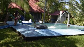 An outdoor swimming pool with a slide, a tire float, and a water fountain.
