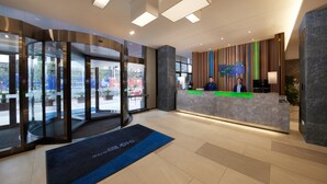 A hotel reception area with a modern design, including a glass revolving door, a reception desk, and a view of the street outside. - Holiday Inn Express Zhangjiagang East by IHG (Suzhou)