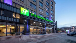 A hotel with a prominent green sign, multiple floors, and a covered entrance area. - Holiday Inn Express Zhangjiagang East by IHG (Suzhou)