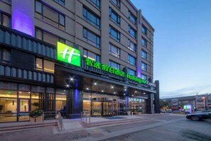 A hotel with a prominent green sign, multiple floors, and a covered entrance area. - Holiday Inn Express Zhangjiagang East by IHG (Suzhou)