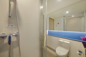 A bathroom with a glass shower enclosure, a toilet, and a sink with a blue countertop.