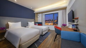 A hotel room with two beds, a desk, a chair, a TV, and a large window offering a city view. - Holiday Inn Express Zhangjiagang East by IHG (Suzhou)