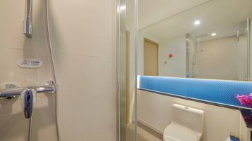Un baño con cabina de ducha de vidrio, inodoro y espejo con encimera de azulejos azules.