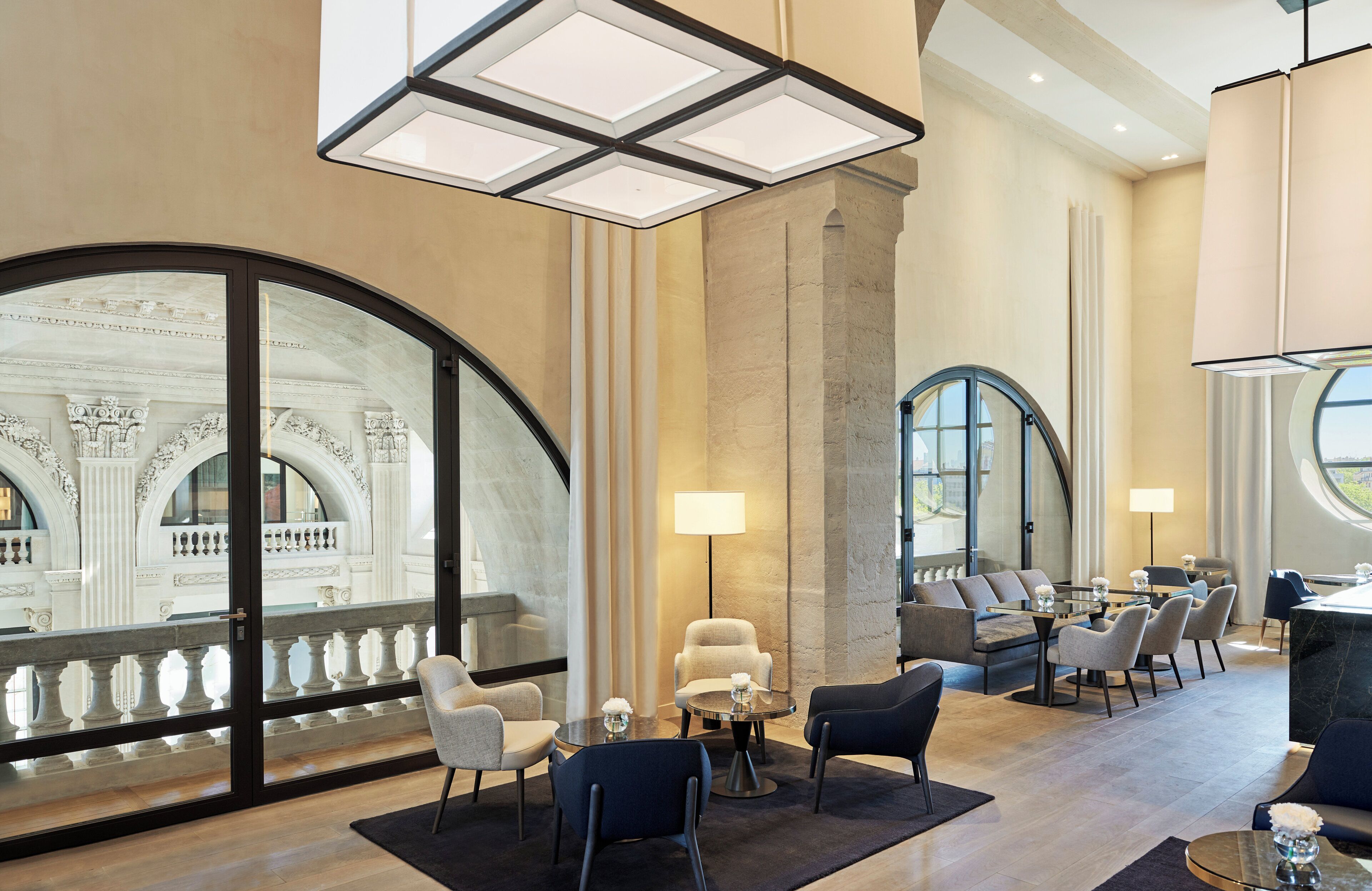 Un hall d’hôtel spacieux, doté d’une grande fenêtre en arc de cercle, d’élégants fauteuils et d’un lustre moderne.