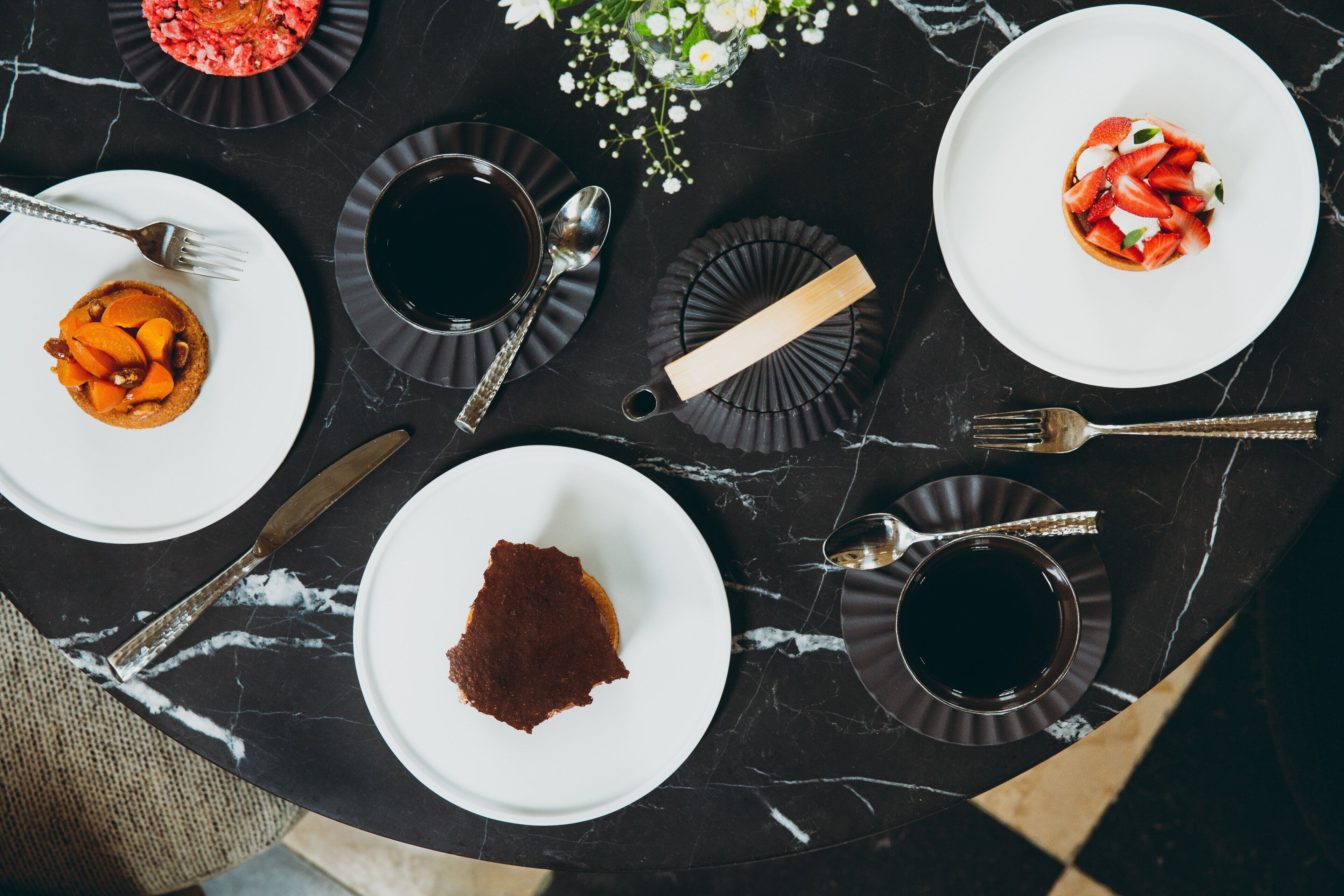 A dining table with plates, cutlery, and a vase of flowers.