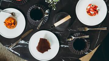 A dining table with plates, cutlery, and a vase of flowers.