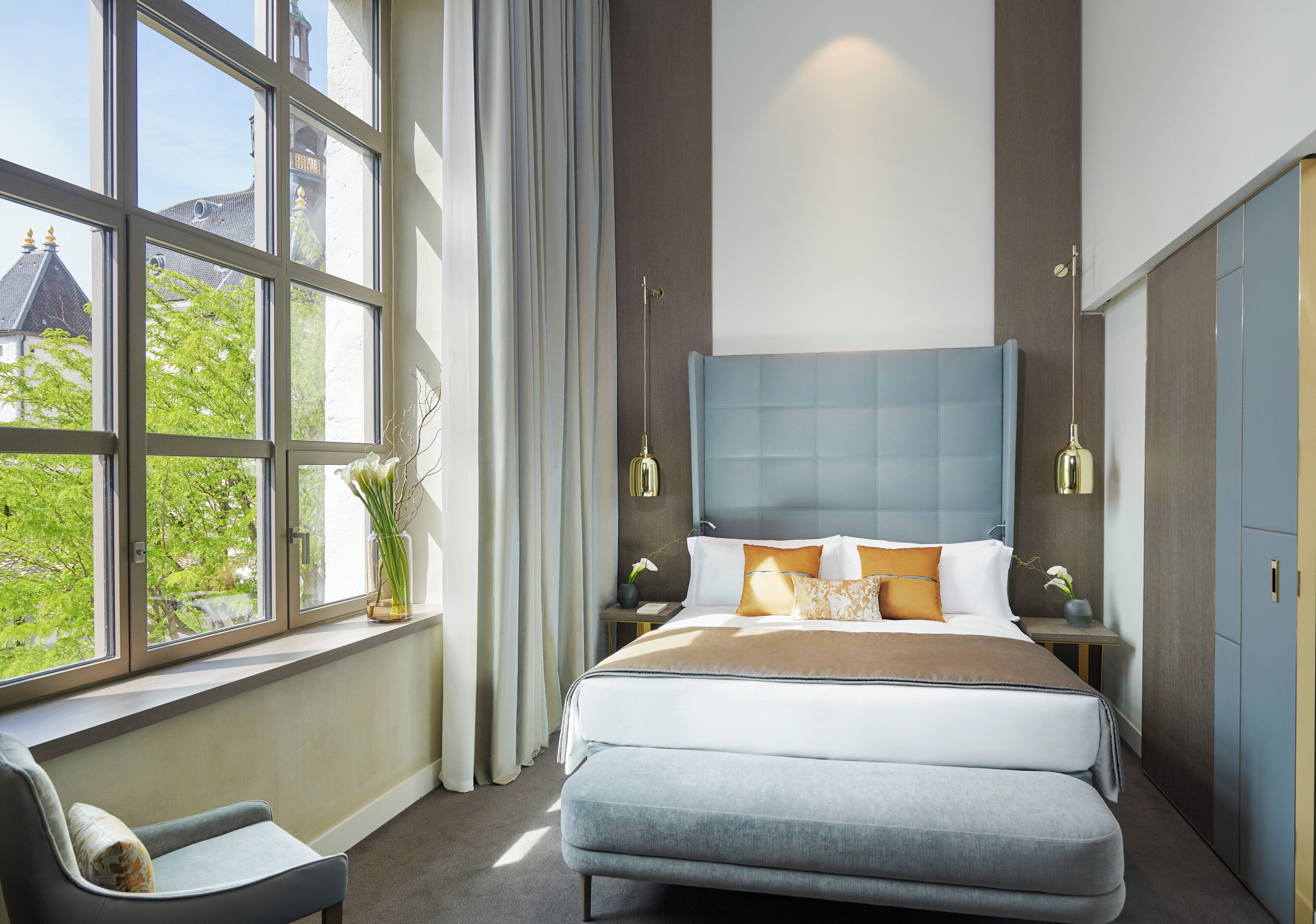 Camera moderna con un ampio letto, una sedia e vista sul verde.