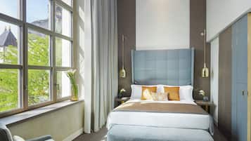 Camera moderna con un ampio letto, una sedia e vista sul verde.