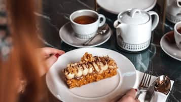 A table with a dessert plate, a teapot, cups, and a tiered dessert stand.